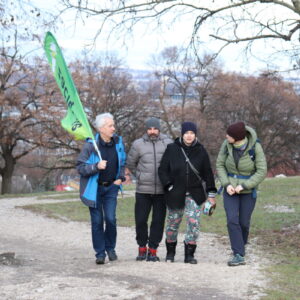 Zdjęcie przedstawia grupę osób z flagą wchodzących ścieżką pod górę.