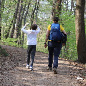 Zdjęcie przedstawia kobietę i dziecko idących ścieżką w lesie.