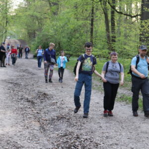Zdjęcie przestawia grupę osób idących po ścieżce w lesie.