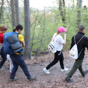 Zdjęcie przedstawia grupę osób idących po ścieżce w lesie.