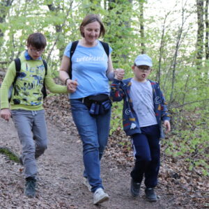 Zdjęcie przedstawia kobietę z dwoma chłopcami z Zespołem Downa schodzących po stromej ścieżce.