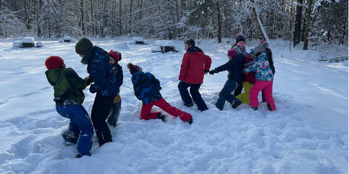Ilustracja przedstawia grupę dzieci bawiących się w śniegu