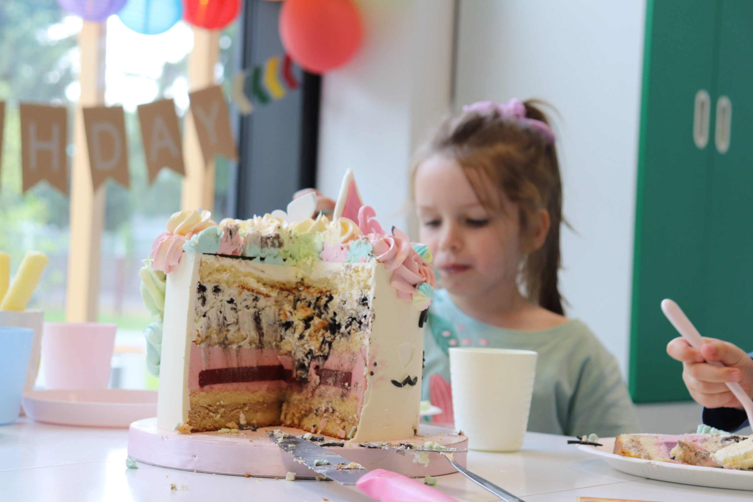 Na zdjęciu jest dziewczynka i jej tort urodzinowy